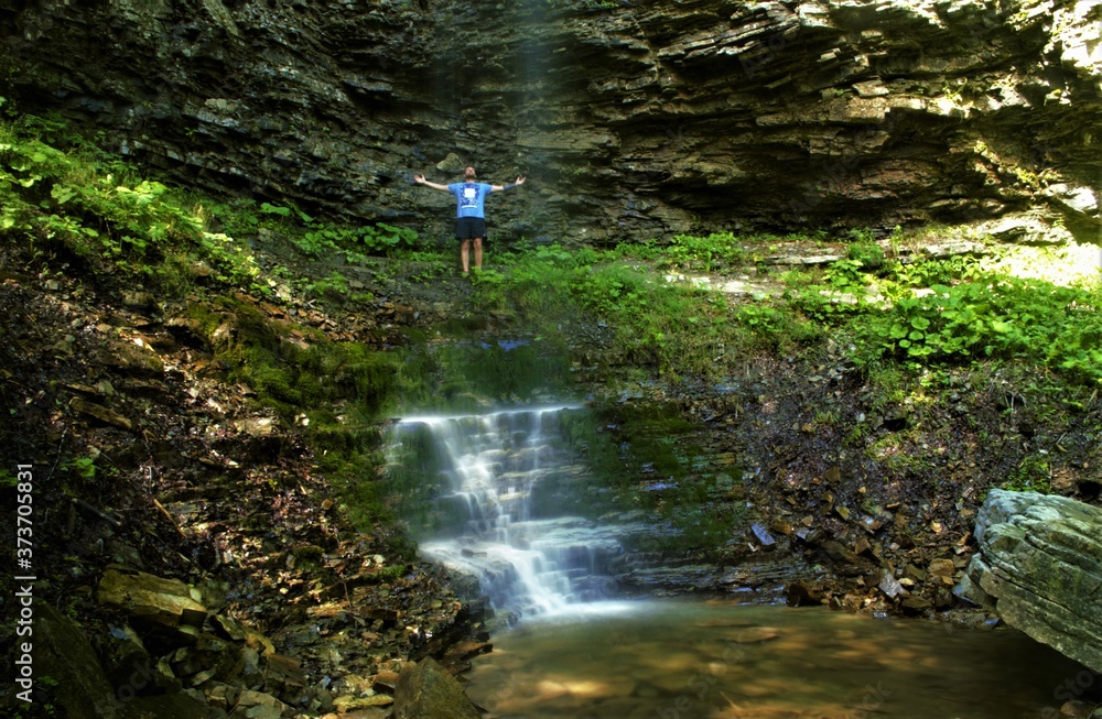 man raised his hands behind the waterfall
man raised his hands behind the waterfall