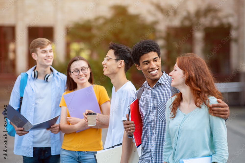 Five multiracial students walking together near campus Five multiracial students walking together near campus