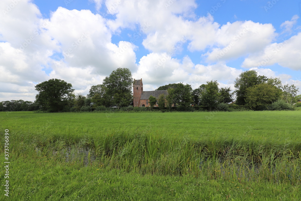 Beautiful panoramic view of a characteristic Dutch church in the green meadows and surrounded by Beautiful panoramic view of a characteristic Dutch church in the green meadows and surrounded by