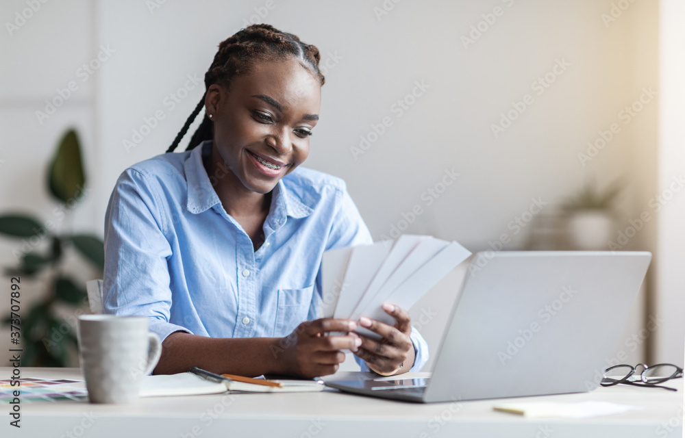 Young black female designer holding and looking at colour swatches