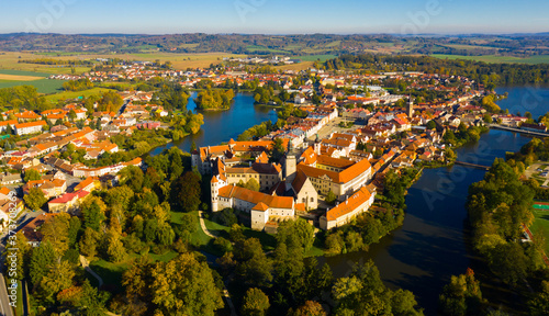 Scenic view from drone of historic part of Czech town of Telc with brownish tiled roofs of houses and medieval Castle surrounded by ponds..