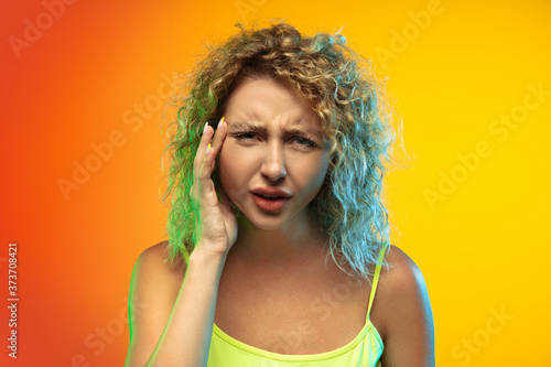Eyeing. Close up caucasian young woman s portrait on gradient studio background in neon. Beautiful female curly model in casual style. Concept of human emotions  facial expression  youth  sales  ad.