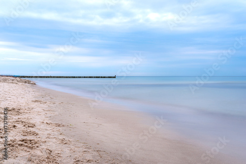 Wooden breakwater covered with moss  arranged in a row at sea  long exposure time  blurred sea waves.