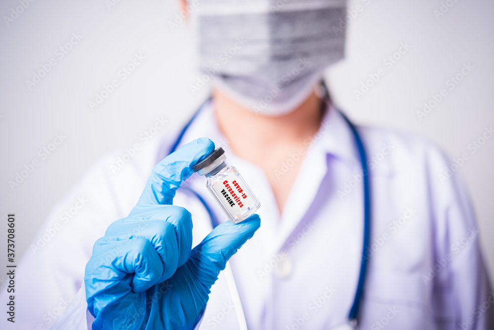 Obraz premium Closeup female woman doctor or scientist in uniform wearing face mask protective in lab use hand finger hold vial vaccine bottle, and on vial vaccine have 
