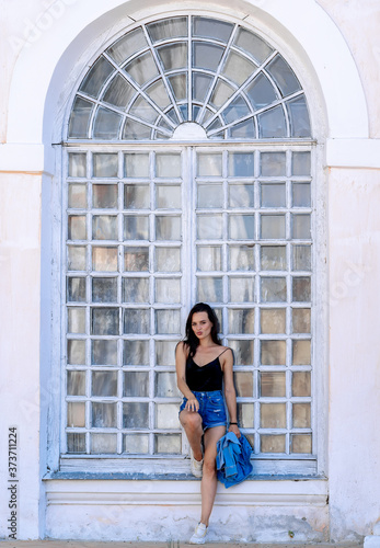 Young girl standing near vintage arque wooden window. Urban style girl. White background. Fashion portrait. photo