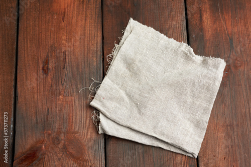 gray kitchen textile towel folded on a brown wooden table from old boards, top view