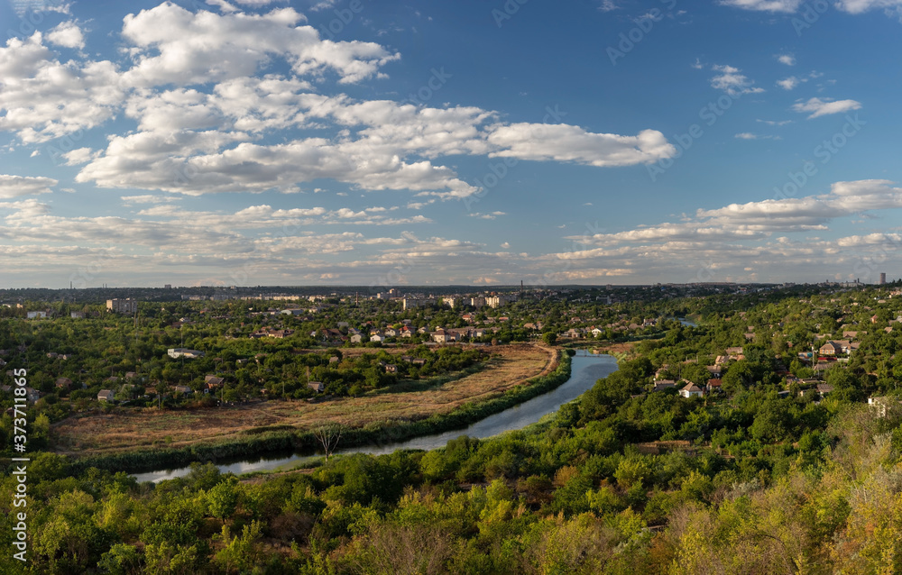 general plan panoramic photo of the urban village landscape, with the river and houses. Green City. Against the backdrop of a cloudy sky with white clouds. general plan panoramic photo of the urban village landscape, with the river and houses. Green City. Against the backdrop of a cloudy sky with white clouds.