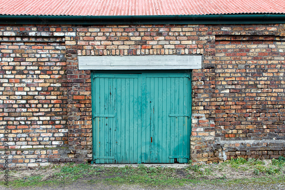 Green painted sliding door on an old abandoned industrial building. Big Pit was a working coal mine from 1880 to 1980. It is now obsolete and closed.