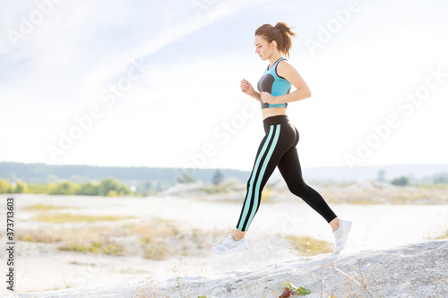 Young fitness runner woman jumping on trail path