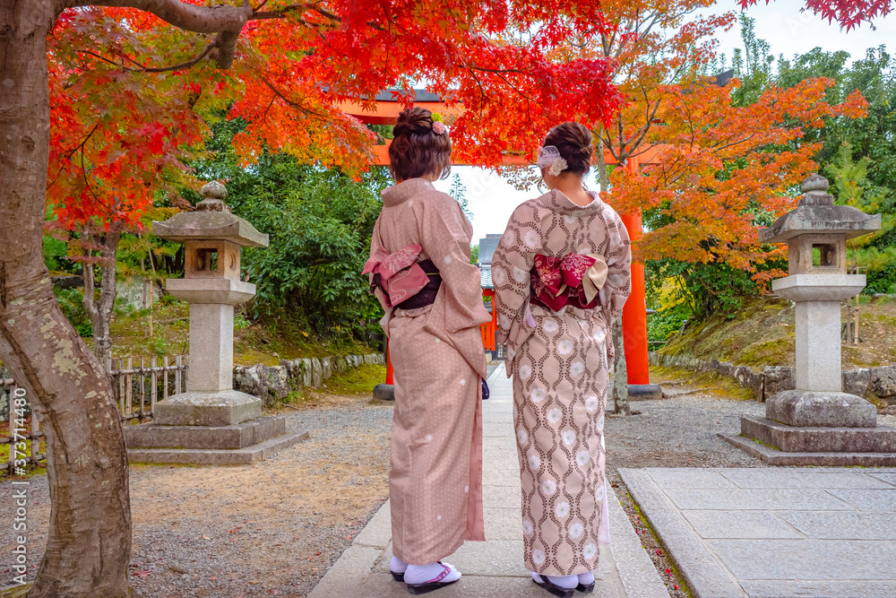 Japanese girls in kimono walking in the Park of Nara. Two Japanese women in national costumes. Women under the red Japanese maple. Nature Park in Nara. Geishas. Sights Of Japan. Autumn walk in Nara.