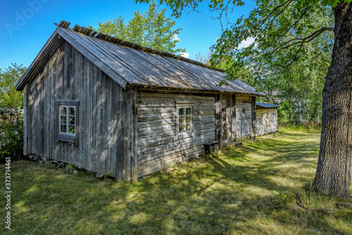 An old weathered timber residential house with greyed wooden roof from one of Turku archipelago island at summer day. Finland.