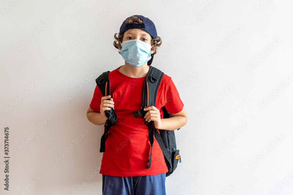 Obraz premium Little boy, elementary school student, going to school with a backpack. New normality at coronavirus, covid-19, time wearing a safety mask. School reopening concept.