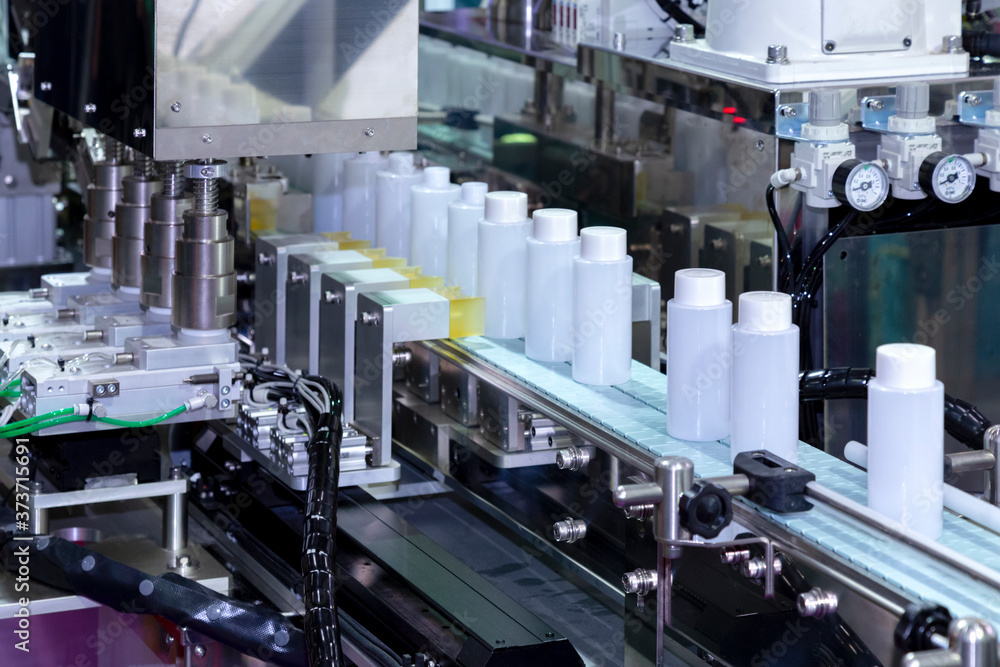 white plastic bottle moving on conveyor belt of auto capping and labeling  machine at cosmetic and skin care manufacturing. cosmetic industry and ai  technology machinery concept. Stock Photo | Adobe Stock