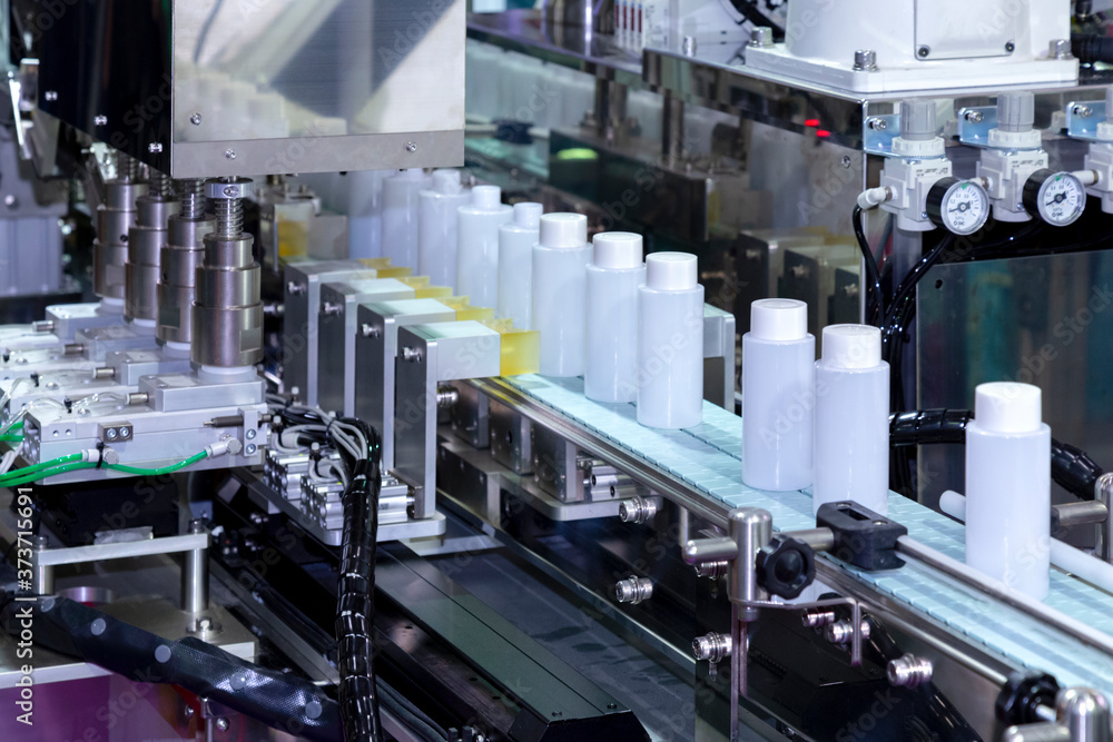 white plastic bottle moving on conveyor belt of auto capping and labeling machine at cosmetic and skin care manufacturing. cosmetic industry and ai technology machinery concept. white plastic bottle moving on conveyor belt of auto capping and labeling machine at cosmetic and skin care manufacturing. cosmetic industry and ai technology machinery concept.