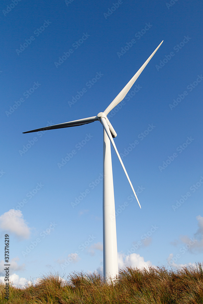 Single wind turbine with blue sky in a vertical format - UK. Clean and renewable energy concept. Single wind turbine with blue sky in a vertical format - UK. Clean and renewable energy concept.