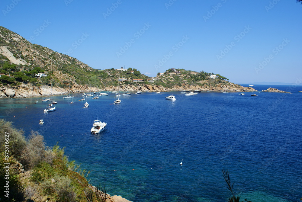 A bay in Giglio Island: the rocky coast and boats off the coast