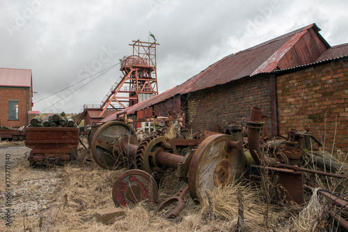 Big Pit was a working coal mine from 1880 to 1980. It is now obsolete and closed. Exterior of an old building with broken and discarded machinery scattered on the ground.

 photo