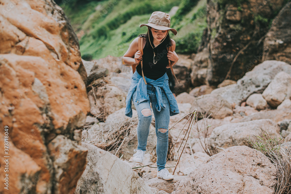 Traveler Asian woman with backpack walking on the rock by river in mountain. Travel and hiking concept