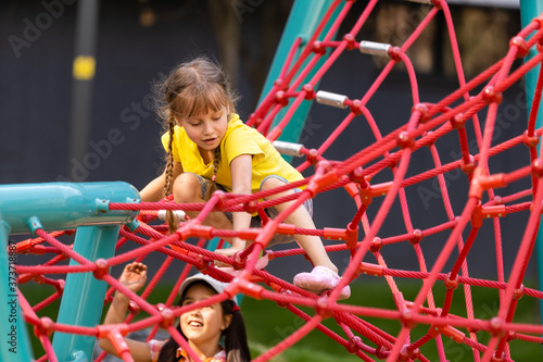 Young girls poking head through climbing rope activity using it as frame.