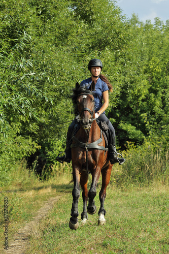 Young woman in uniform and helmet riding horse. Equestrian sport - dressage. © horsemen