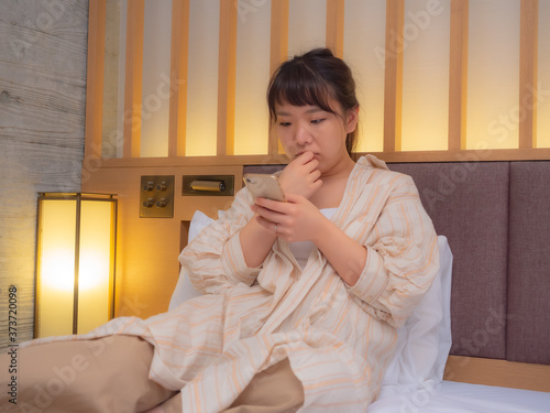 ベットでスマホを操作する女性