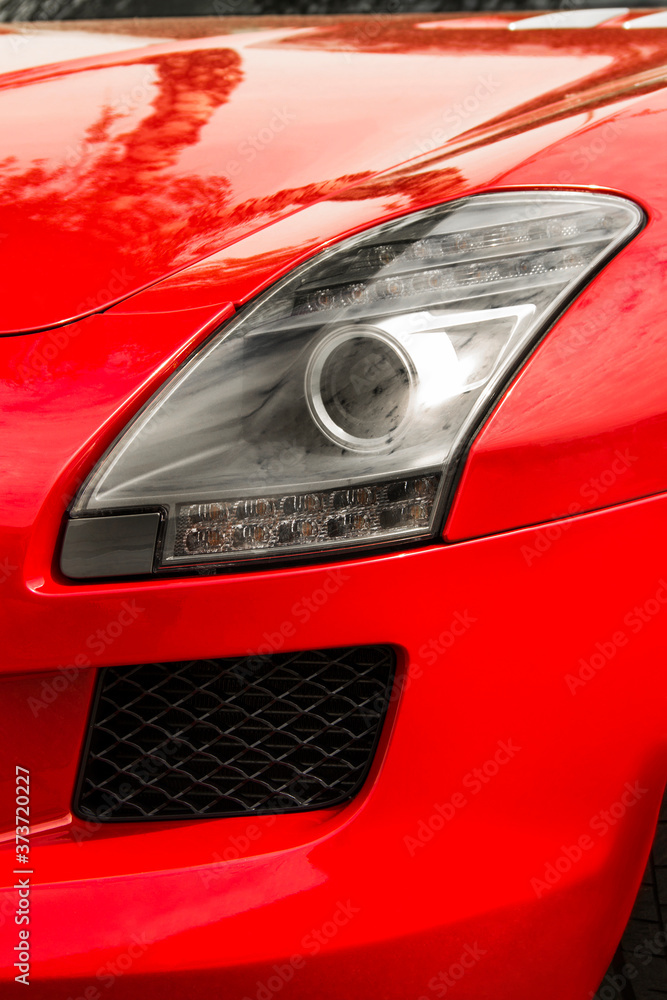 Car headlights. Luxury Headlights. Part of a red car close up. Bumper