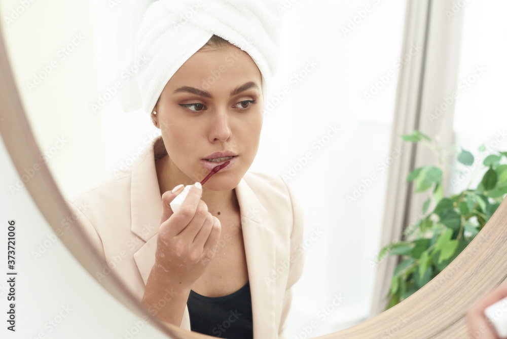 Young woman preparing to party, getting ready for going out. Beautiful young woman applying lipstick and looking at her reflection in mirror Young woman preparing to party, getting ready for going out. Beautiful young woman applying lipstick and looking at her reflection in mirror