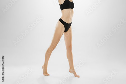 Beautiful female legs and belly isolated on white background. Beauty, cosmetics, spa, depilation, treatment and fitness concept. Fit and sportive, sensual body with well-kept skin in underwear.