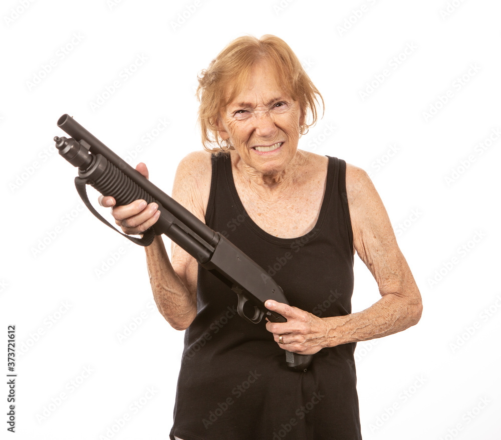 Mature senior woman with a shotgun, facing the camera with a scowl on her face. Mature senior woman with a shotgun, facing the camera with a scowl on her face.
