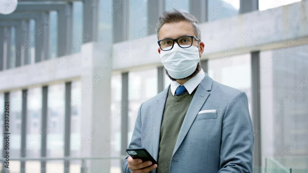 Businessman with smartphone going on business trip, wearing face mask at the airport. Businessman with smartphone going on business trip, wearing face mask at the airport.