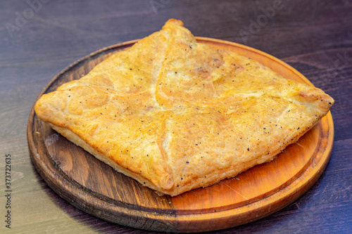 Freshly baked khachapuri with cheese on a round wooden tray Georgian dish khachapuri. Young imeritin cheese is used as a filling. National cuisine, traditional Georgian food. Adjara, Georgia, Eurasia