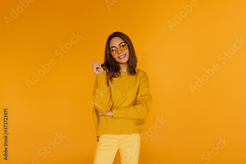 Appealing girl in yellow pants smiling to camera. Gorgeous caucasian female model in glasses enjoying photoshoot. © Look!