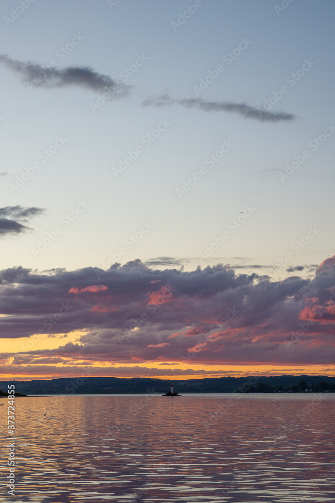 lighthouse on reflective lake with magenta stormy skies lighthouse on reflective lake with magenta stormy skies