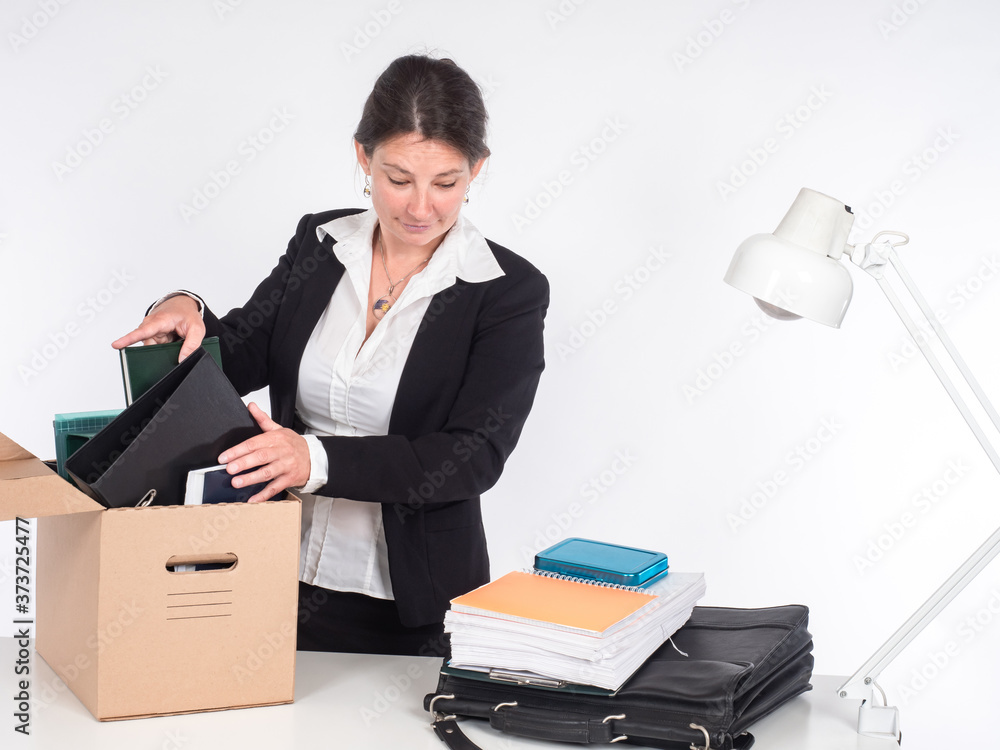Dismissal from work. The girl leaves the workplace. A woman collects things from the desktop in a cardboard box. Job loss. Redundancy. Unemployment.