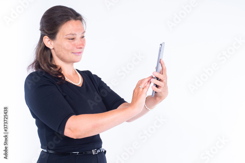 The girl looks at the information on the tablet. A woman in a black dress holds a tablet in her hands. Girl with a tablet on a white background.