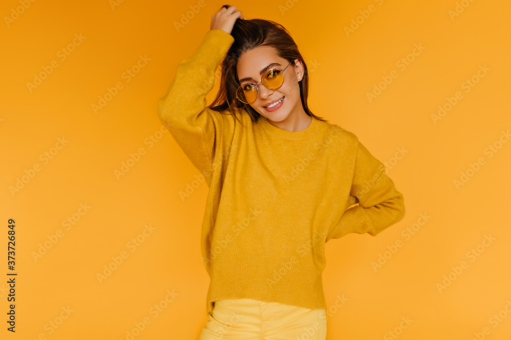 Pleased good-humoured girl in sweater posing with interested smile. Studio shot of glad brunette lady in sunglasses. Pleased good-humoured girl in sweater posing with interested smile. Studio shot of glad brunette lady in sunglasses.