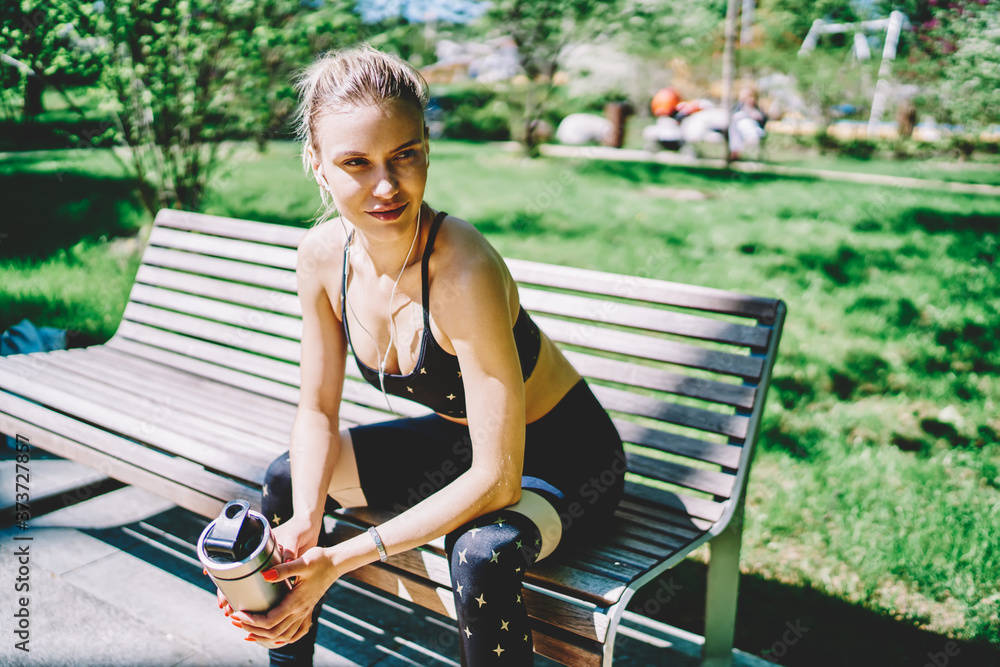 Young sportive lady sitting on bench in park