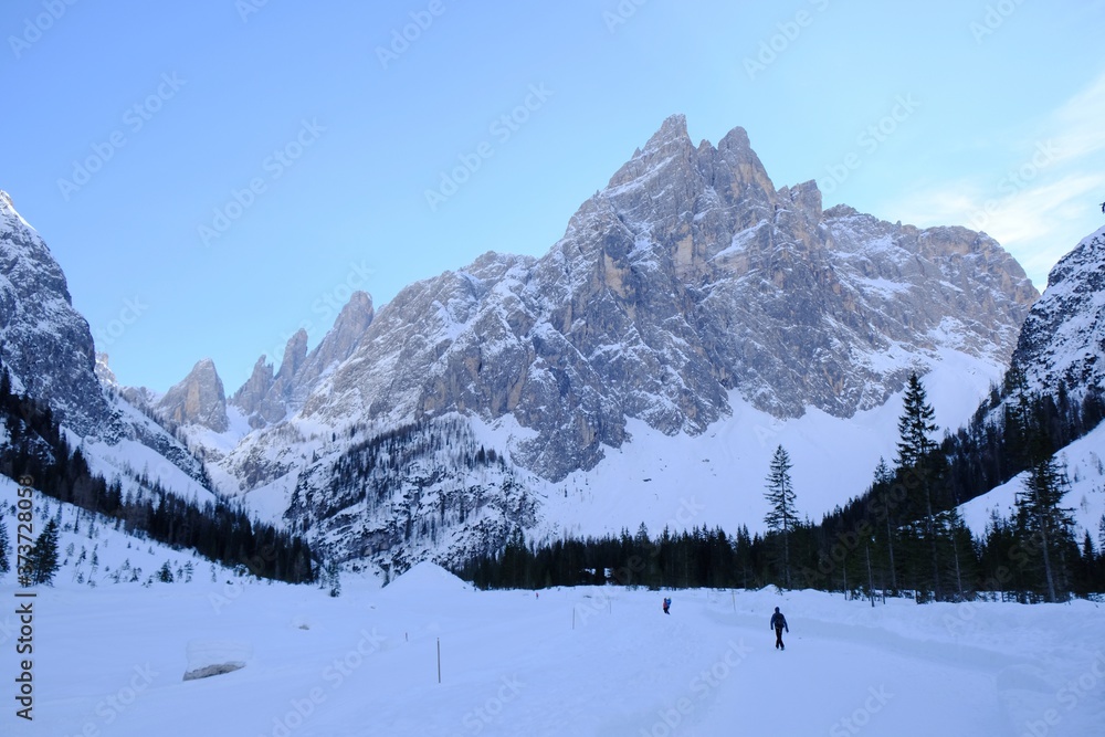 Cross-country skiers in the beautiful mountain valley of Val Fiscalina. The mountains are lit by the evening sun. Sexten Dolomites, South Tyrol, Italy