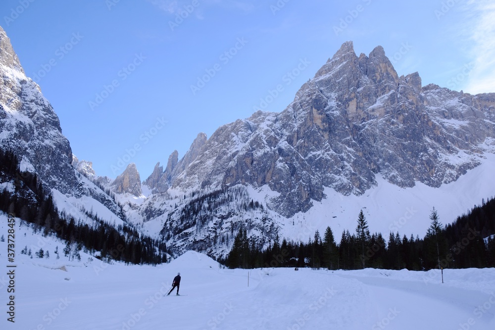 Cross-country skier in the beautiful mountain valley of Val Fiscalina. The mountains are lit by the evening sun. Sexten Dolomites, South Tyrol, Italy