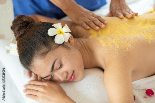 Beautiful Asian woman having exfoliation treatment with body scrub in spa salon, scrubbing and skin care concept, enjoying and relaxing time