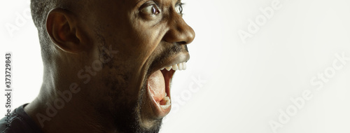 Screaming. African-american young man's close up shot on studio background, flyer. Concept of human emotions, facial expression, sales, ad. Copyspace. Beautiful male model with bright expression.