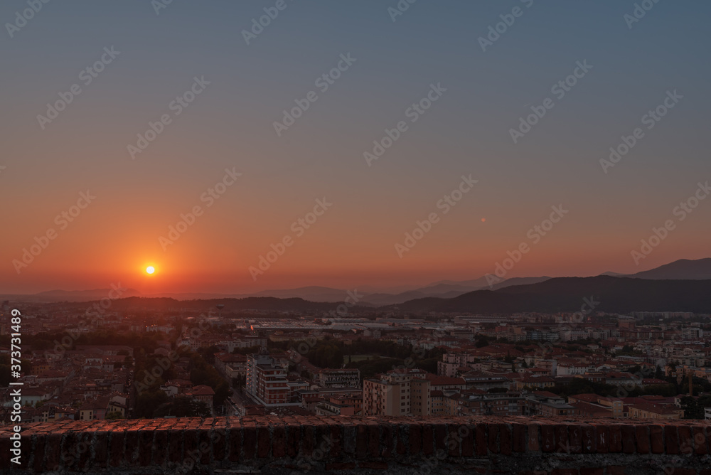 erial panoramic sunset view of residential district with buildings of Brescia city and Alps mountain range, blue cloudy sky background, Lombardy, Italy. Brescia Castle.