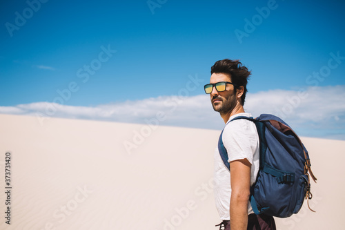 Half length of traveler enjoying beauty scenery in White sands national Park during hot day, South Asian tourist in sunglasses exploring dune in desert looking at camera during getaway summer journey