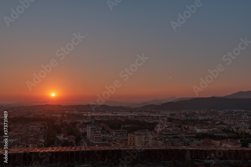 erial panoramic sunset view of residential district with buildings of Brescia city and Alps mountain range  blue cloudy sky background  Lombardy  Italy. Brescia Castle.