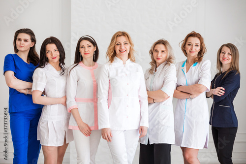 Beautiful young female doctors in white uniforms posing against the background of a white wall.