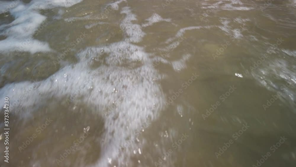 Brown ocean water pulled by tide as white foam wave rolls in, Closeup Tilt Down Brown ocean water pulled by tide as white foam wave rolls in, Closeup Tilt Down