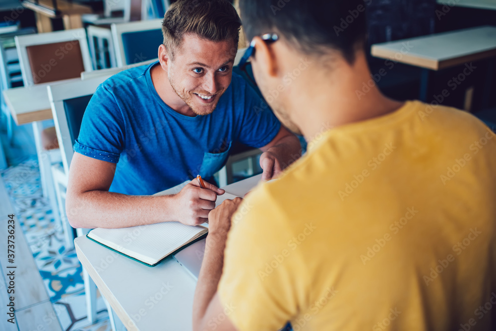 Φωτογραφία Cheerful caucasian male journalist writing notes during conversation interview with man in coffee shop satisfied with job and friendly talk, positive hipster guys cooperating making research together