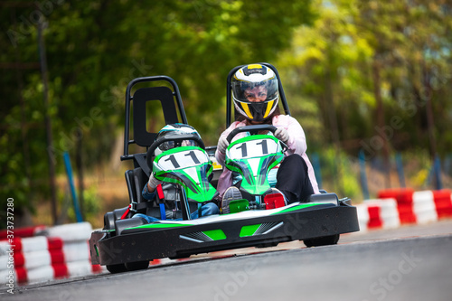 Adult and child in helmets driving karting on track