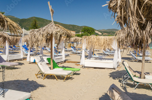 Straw beach umbrellas and sun chairs on a sandy beach on the east coast of Zakynthos island in Greece