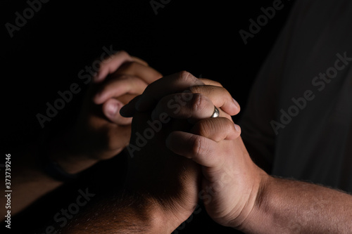 Emotional detail of two men holding hands in dark background